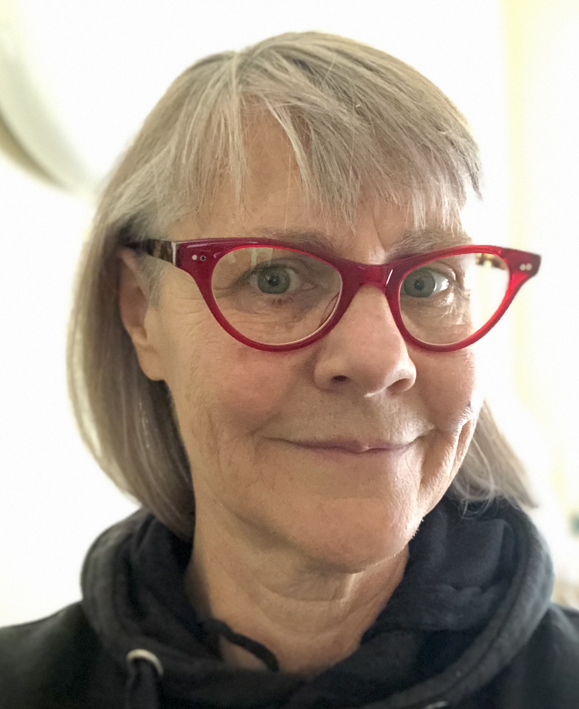 Person with grey hair and red glasses