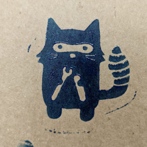 Image of a critter cartoon holding tools stamped in black ink on a beige surface.