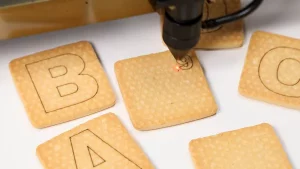 Laser engraving square alphabet cookies.