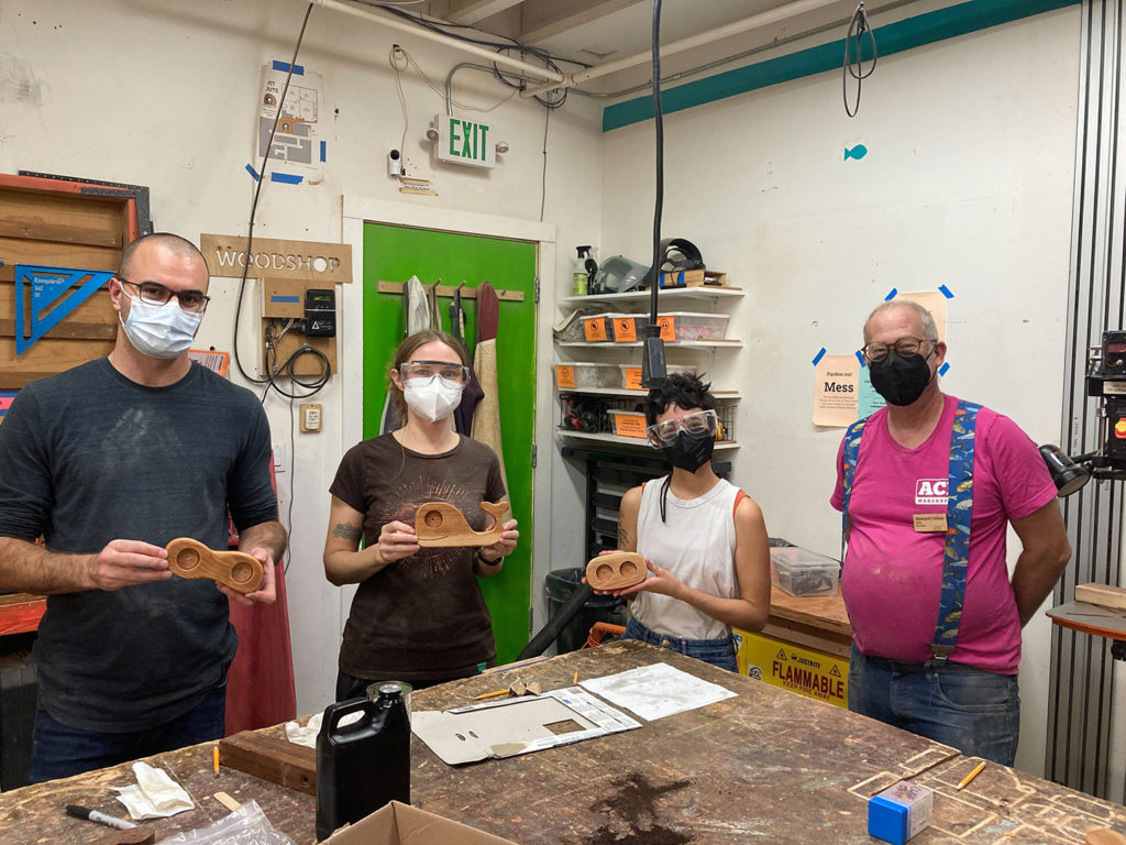 Teacher with 3 students holding sculpted wood candle holder projects.