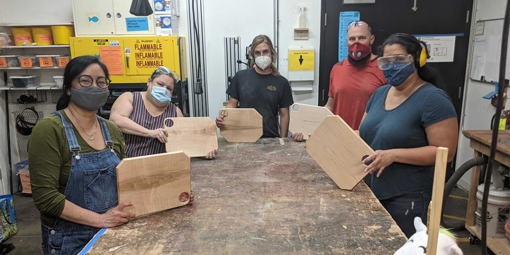 Five people showing off Solid Wood Cutting Boards in the Ace Workshop.