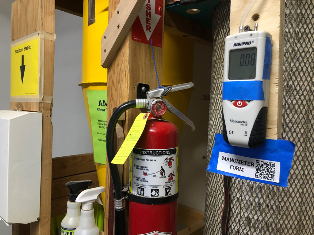 Manometer with QR code next to a cyclone dust collector. 