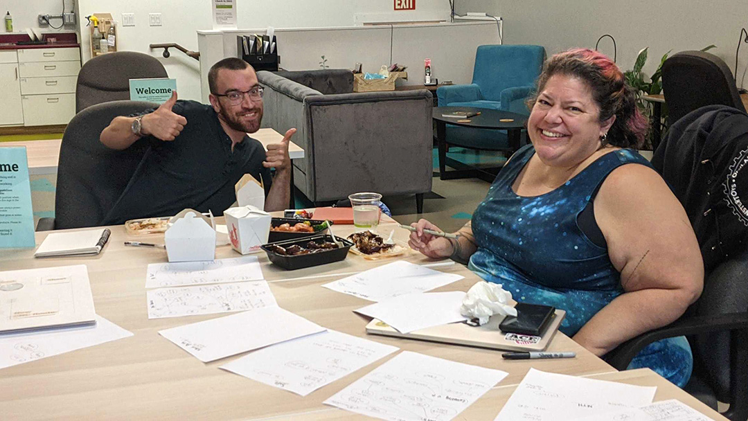 Smiling people at table with takeout and documents. 