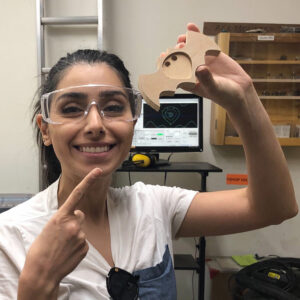 Smiling person with protective googles and carved wooden bat. 