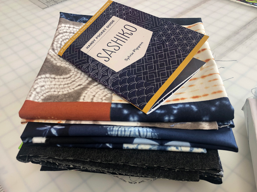 Pile of fabric and "Sashiko Handy Pocket Guide"
