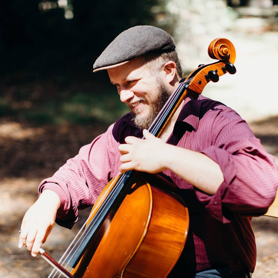 Person in red shirt playing cello.