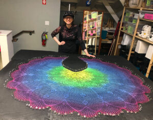 Artist posing with blocked, shawl with scalloped edge