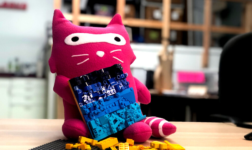 stuffed pink raccoon with a blue lego mosaic