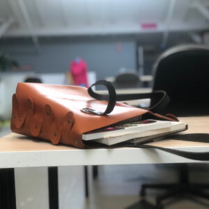 Leather tote bag spilling out books onto a table