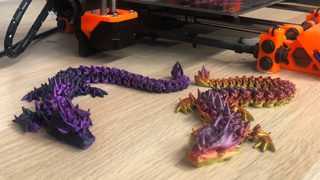 Purple and rainbow 3D printed dragons on table