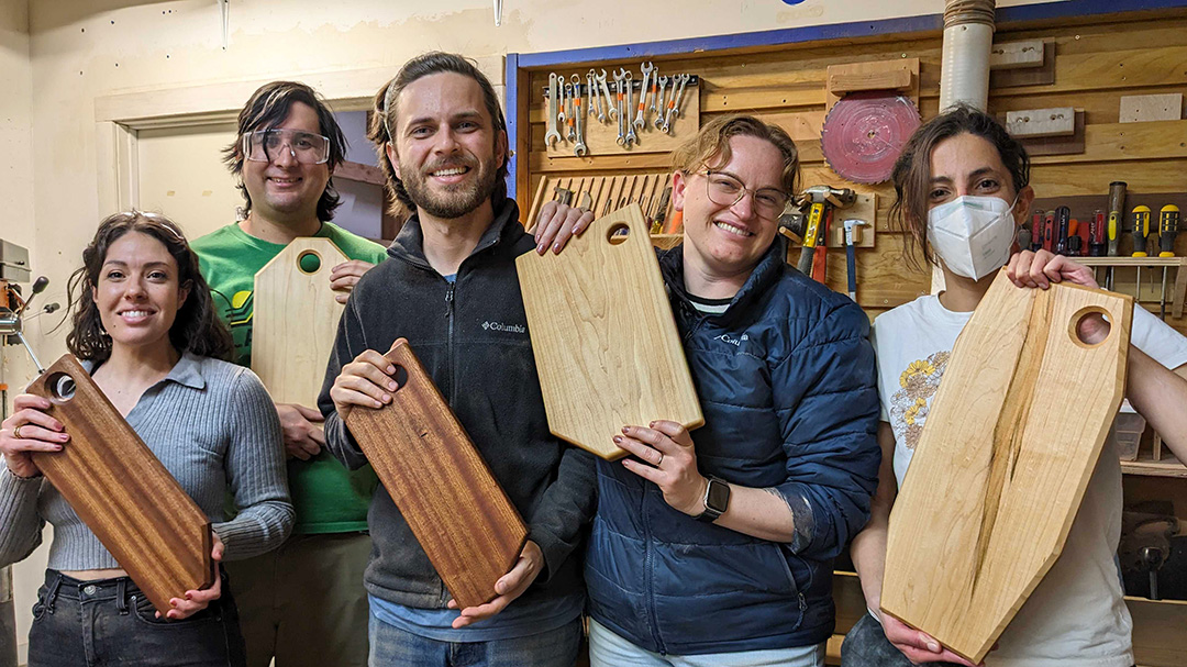 Folks holding wood cuttingboards in workshop