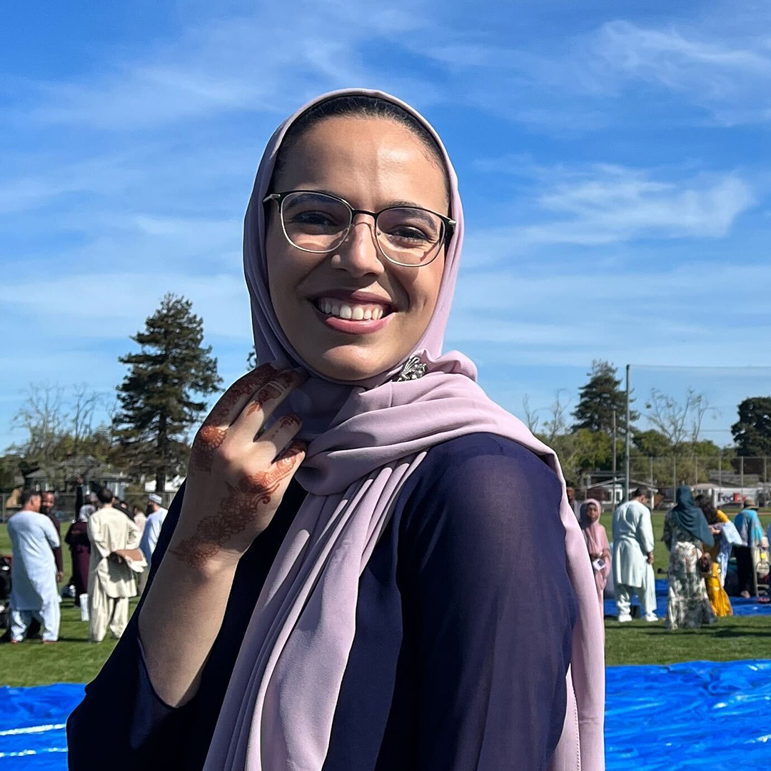 Person dressed in purple smiling outside.