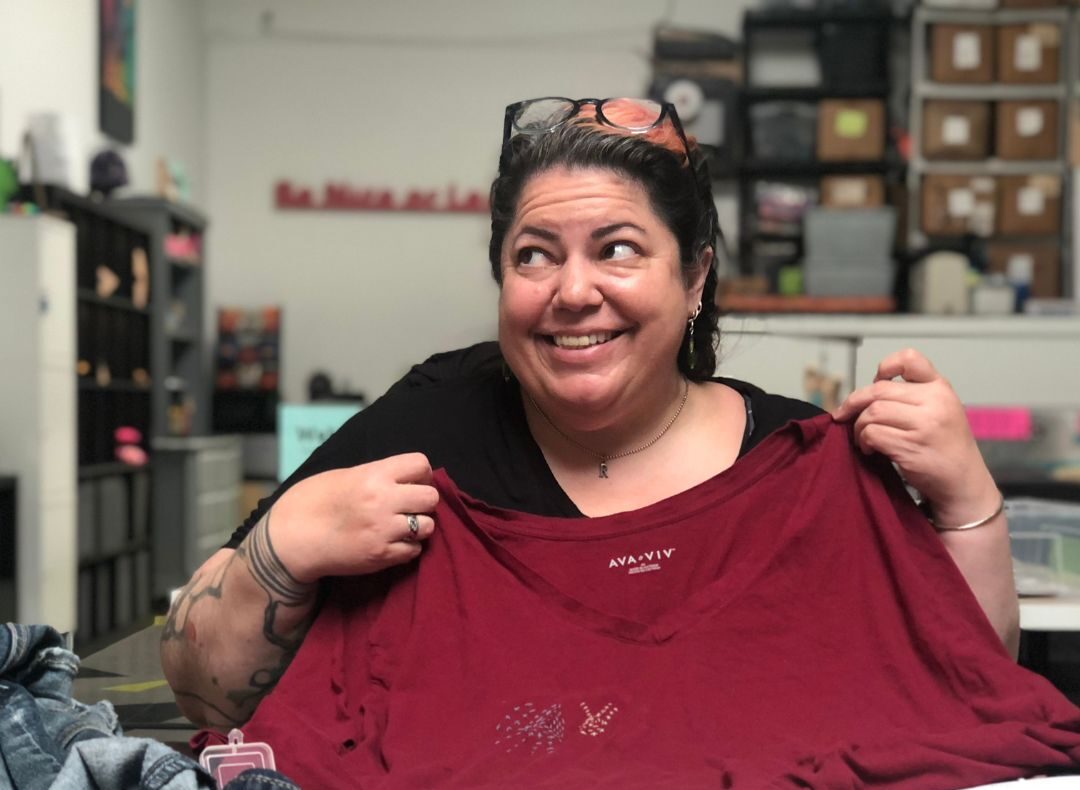 Person smiling holding up red T-shirt. 